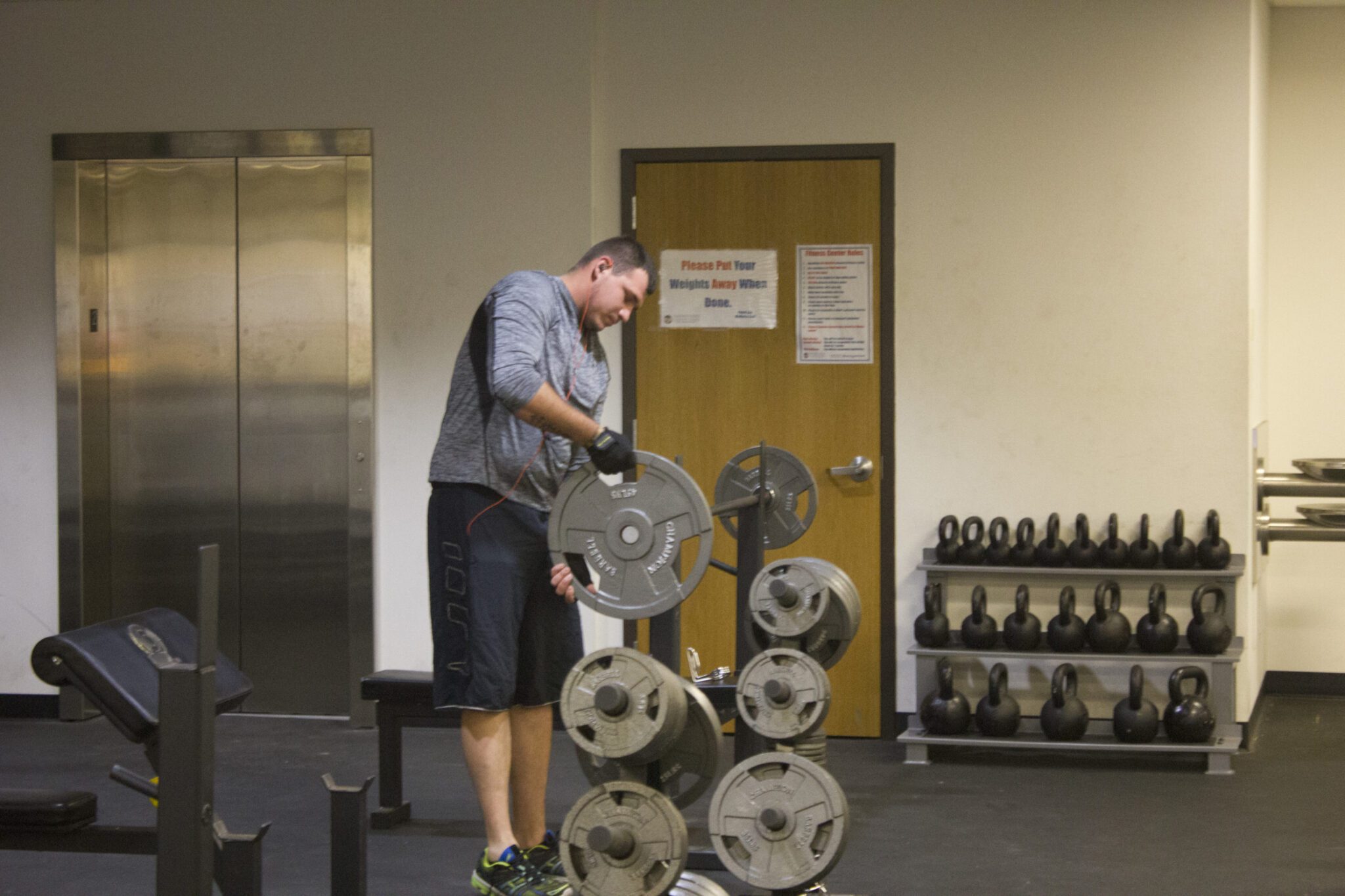 A man reracking weights in a gym.