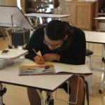 A student taking notes while reading his textbook.