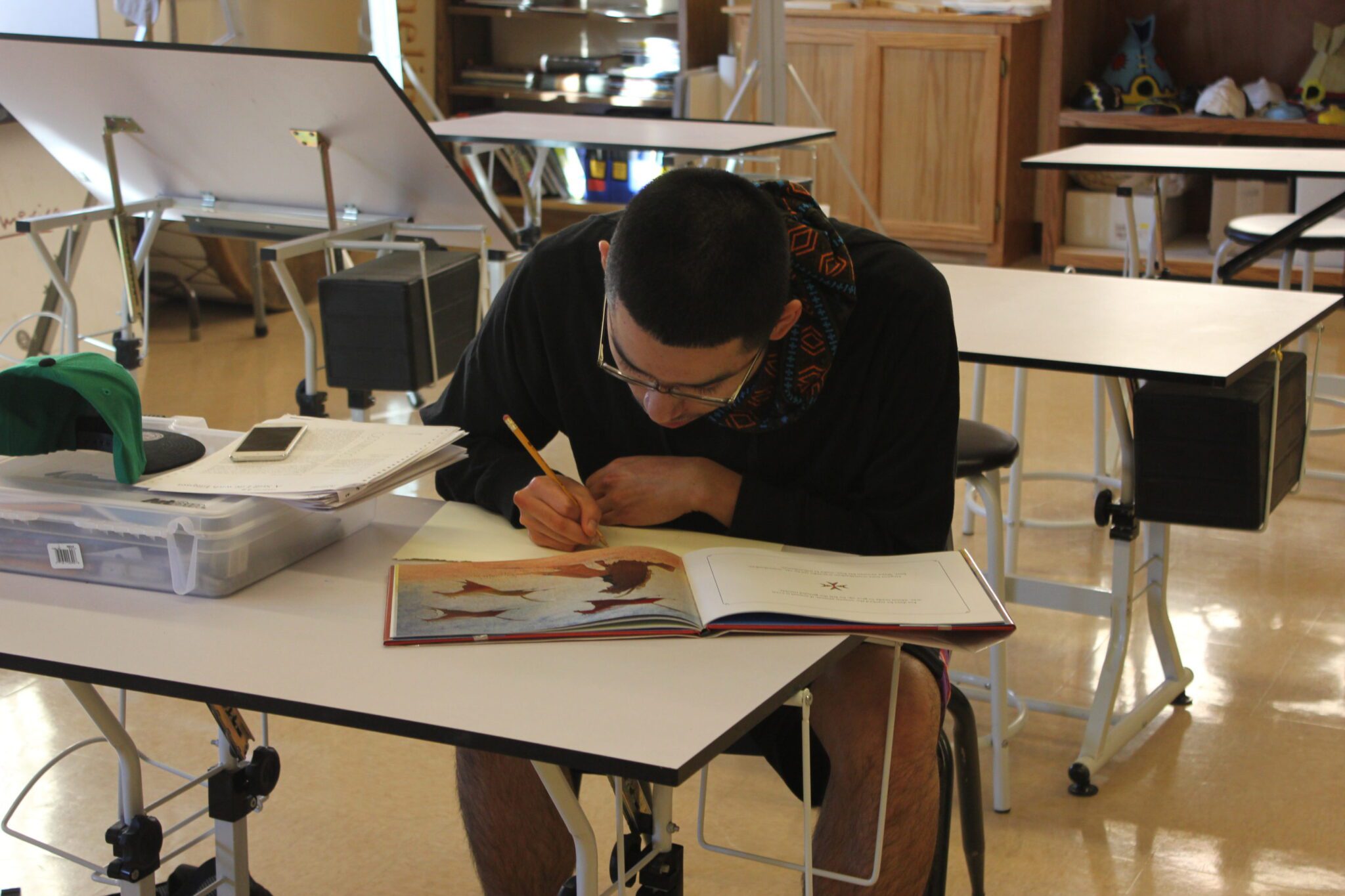 A student taking notes while reading his textbook.