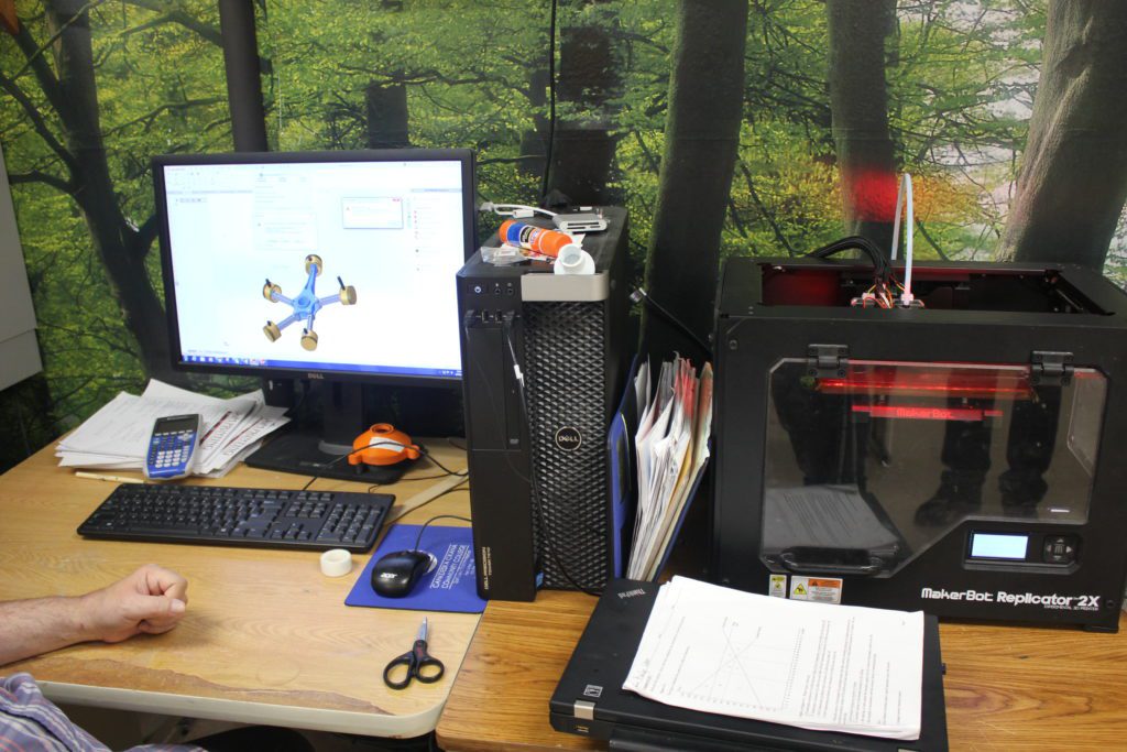 A student printing items using a 3-D printer.