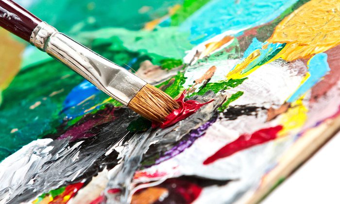 a paintbrush mixing paint on a paint board.