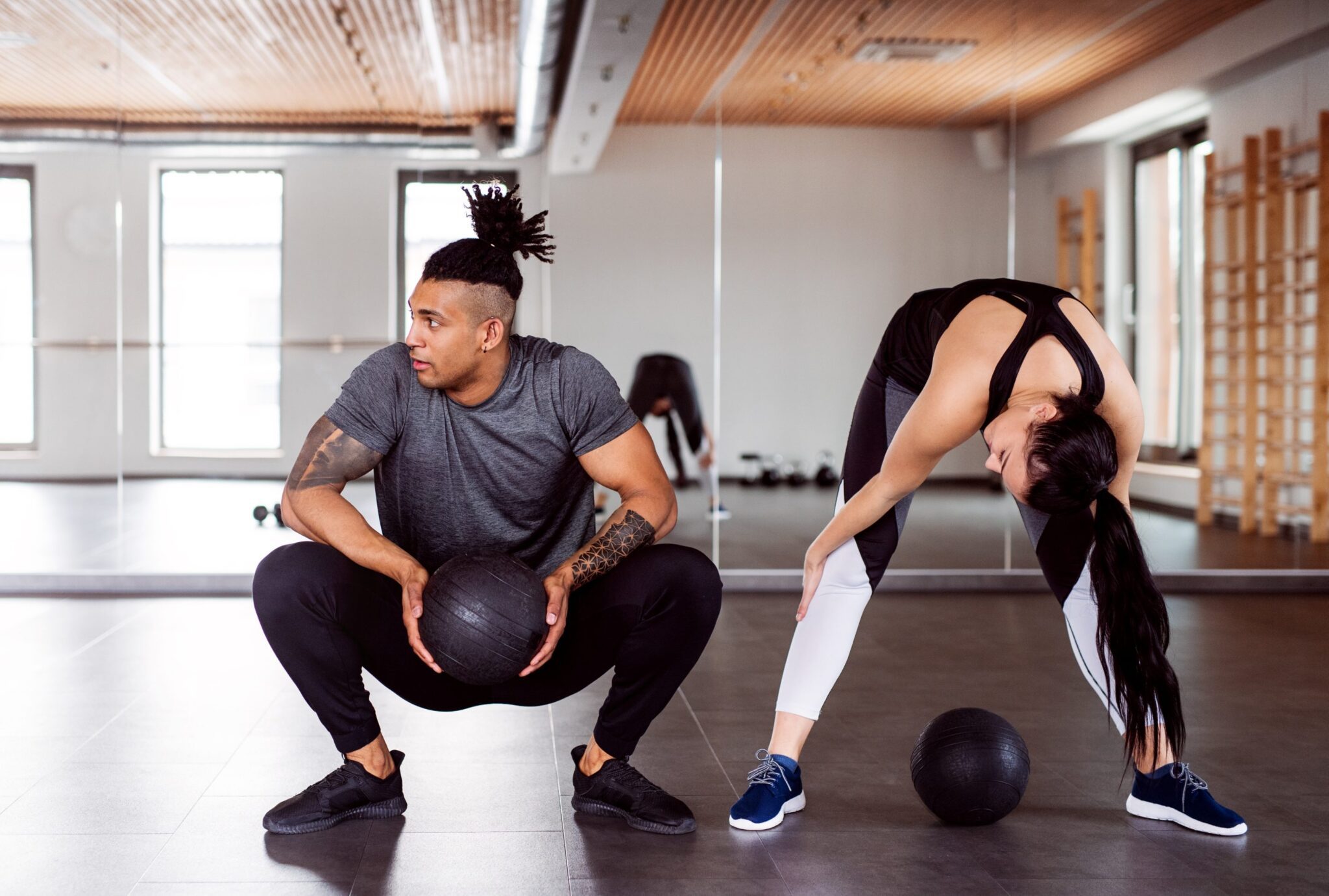 A man and woman working out with medicine balls.