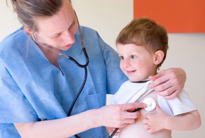 A nurse checking a young boy's heartbeat.